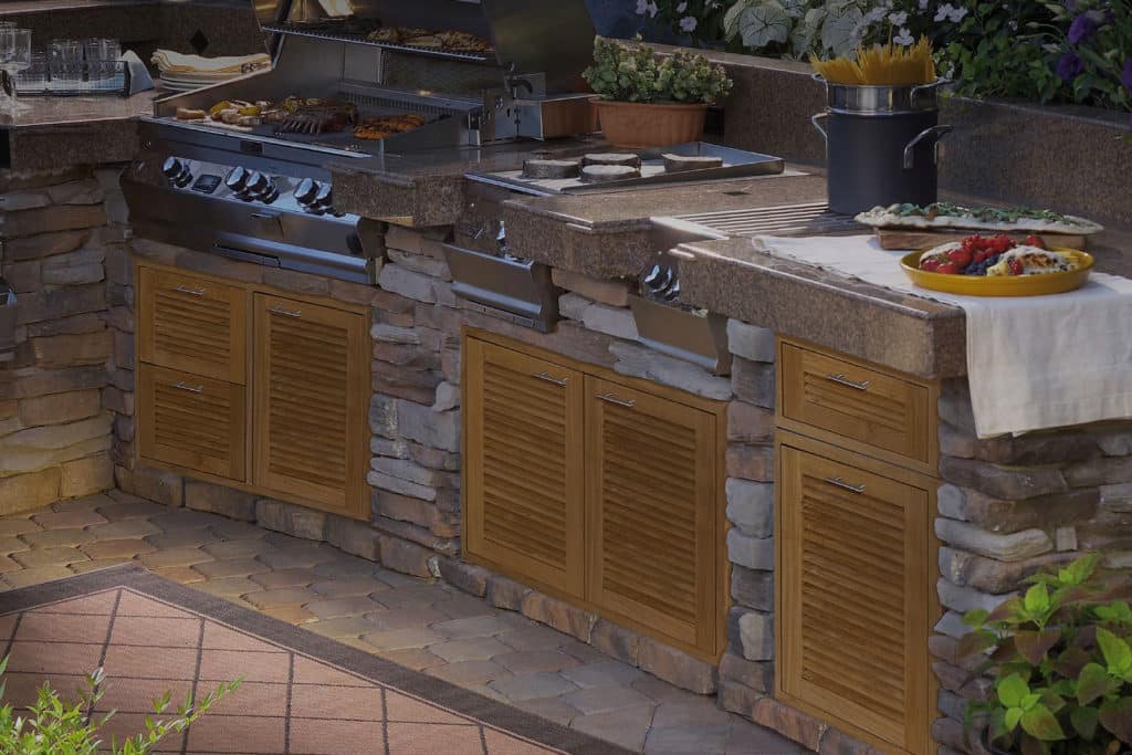 Outdoor kitchen counter with stone base and louvered teak cabinets