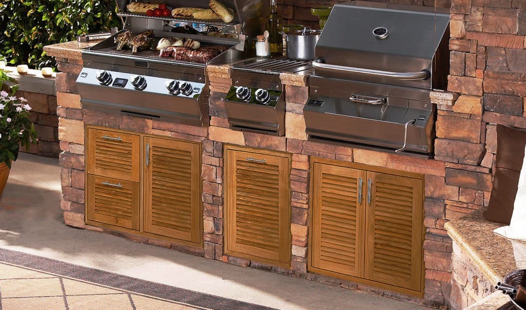 Angled view of a stone outdoor kitchen with louvered teak doors